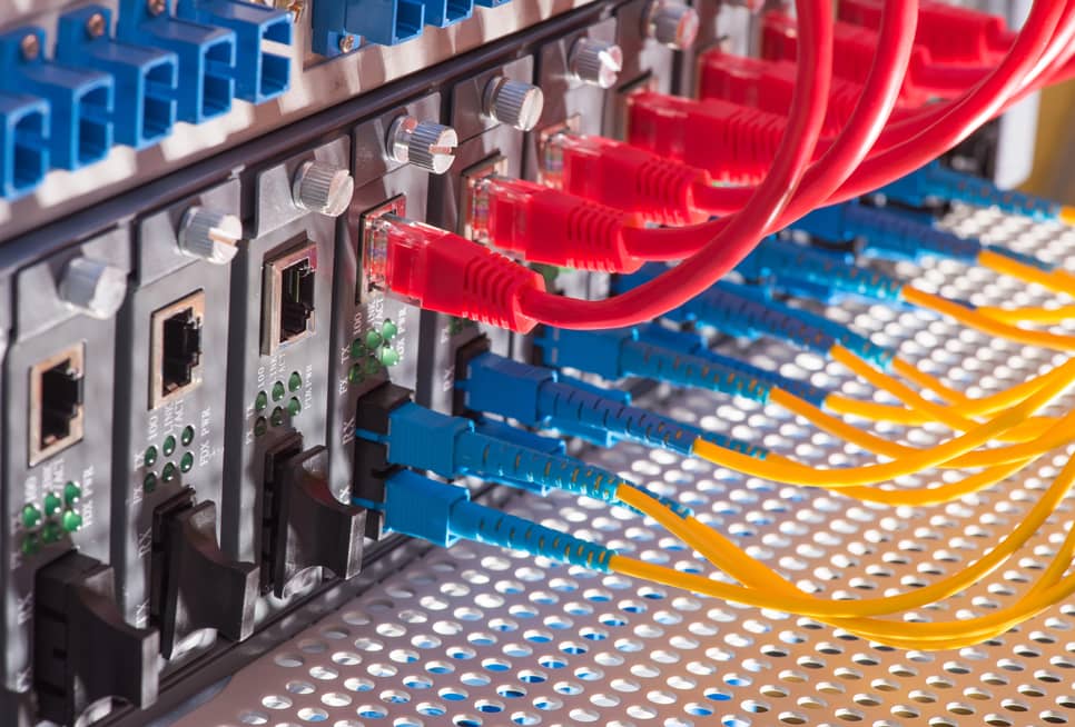 Cables de fibra óptica y ethernet conectados a un router, representando la infraestructura de una WAN.