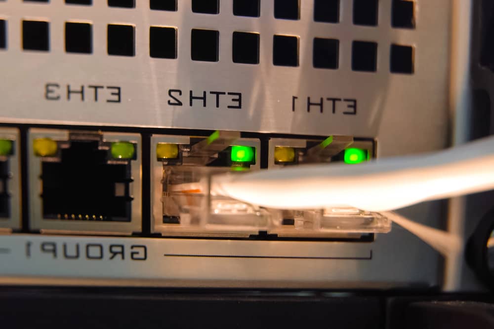 Cerca de puertos Ethernet iluminados con cables conectados, ilustrando el "Concepto de ethernet backhaul" para redes.