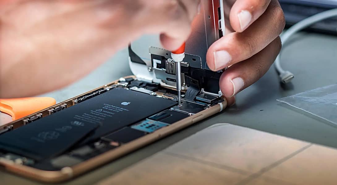 Primer plano de un técnico arreglando un smartphone, una práctica que promueve el derecho a reparar móviles y la sostenibilidad.