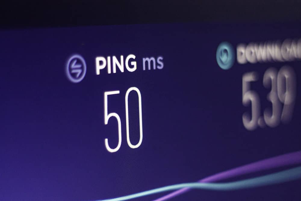 Pantalla mostrando un resultado de "PING 50 ms" y velocidad de descarga, ilustrando cómo usar el ping para medir latencia de red.