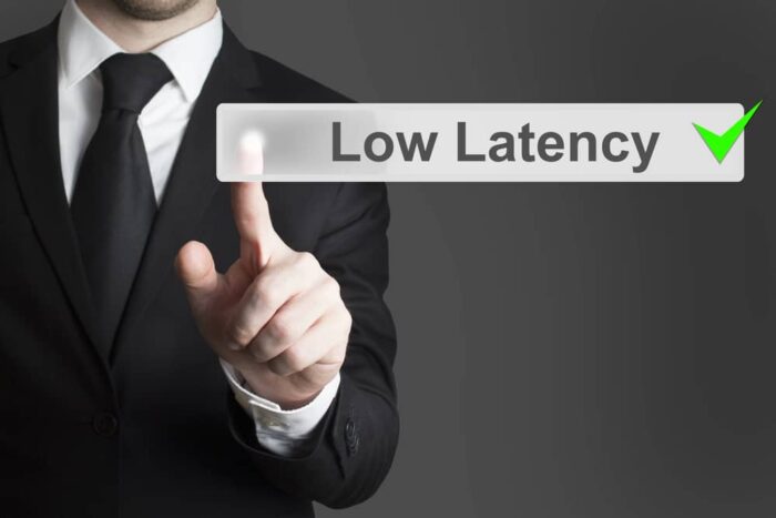 Hombre de negocios señalando un botón digital baja latencia (Low Latency) con una marca verde de aprobación, simbolizando eficiencia.