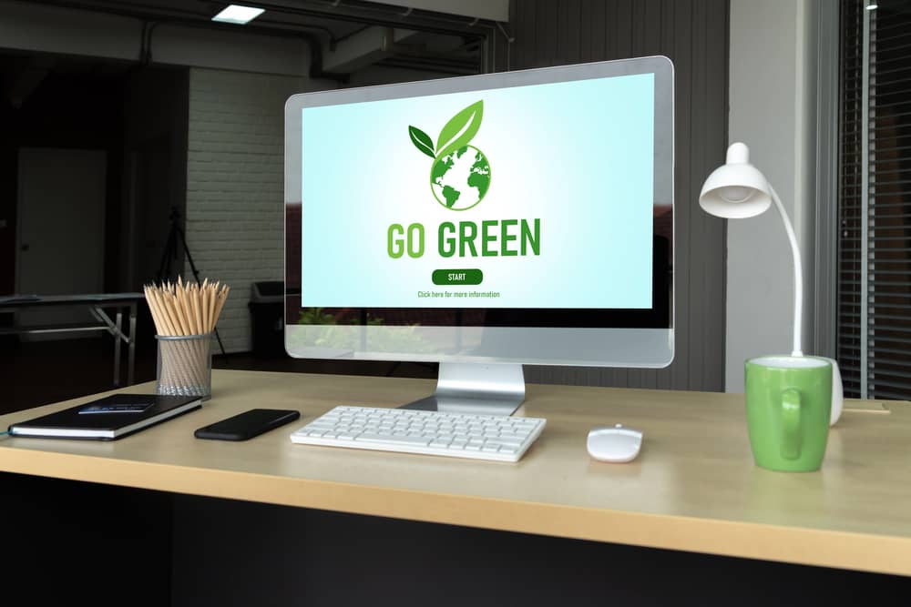 Computadora de escritorio con el lema 'Go Green' en la pantalla, simbolizando técnicas sostenibles para un sitio web ecológico.